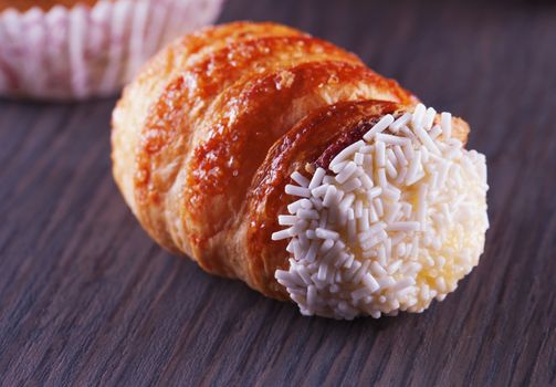 A pastry "cannolo" over a dark wood table