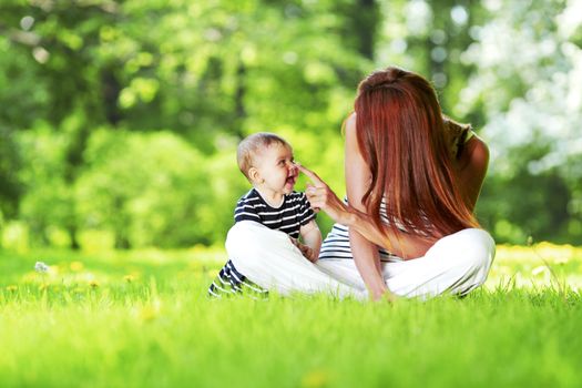 Mother and daughter sitting on grass in spring park