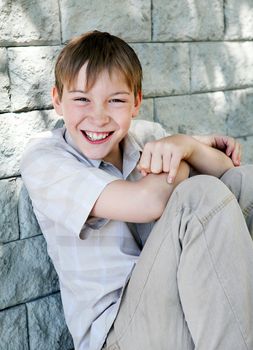 Cheerful Kid sitting by the Wall of the House