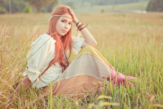 Country hippie girl sitting at golden field
