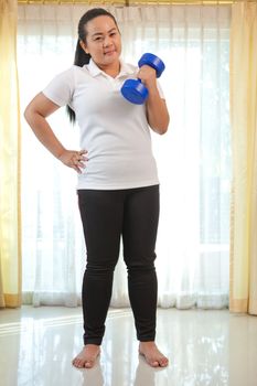Young asian fat woman does fitness with dumbbell in home
