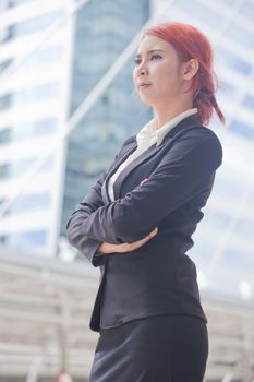 Portrait of young business asian woman standing and smiling arms crossed in modern city