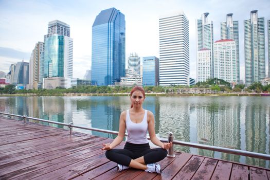 Young asian woman doing yoga exercises at the city park