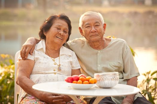 Happy Asian Senior couple sitting outdoors on sunset