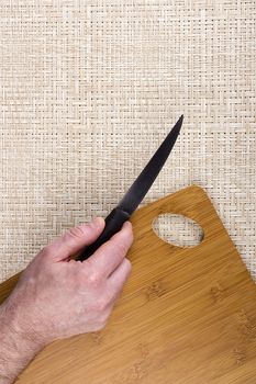 Kitchen knife on a table with a cutting board.