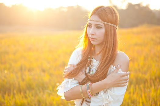 Hippie woman posing in golden field on sunset