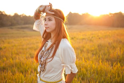 Hippie woman posing in golden field on sunset