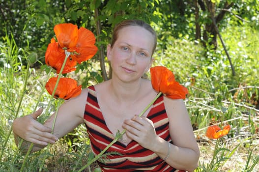 The woman with red poppies in a garden