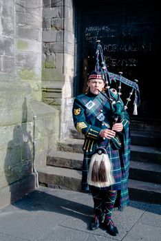 EDINBURGH, SCOTLAND - May 31,2014: Scottish Bagpiper playing his bagpipe on May 31, 2014 in Edinburg, Scotland - the most popular tourist city destination in Scotland.