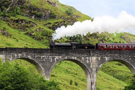 GLENFINNAN, SCOTLAND - June 5, 2014: A steam train on famous Glenfinnan viaduct, well known through Harry Potter as Hogwarts Express on June 5, 2014 in Glenfinnan, Scotland, Great Britain.