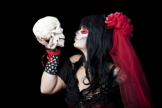 Day of The Dead.  A woman dressed as a sugar skull kissing the skull of a departed love one.