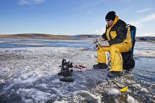 Man ice fishing on a frozen Canadian lake.