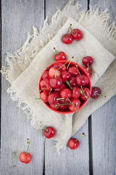 An overhead shot of a bowl of cherries in a rustic setting.
