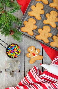 Gingerbread cookies being decorated on a raw, weathered wood background.