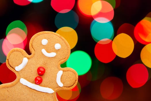 A freshly baked and decorated gingerbread man with a beautiful Christmas bokeh background.