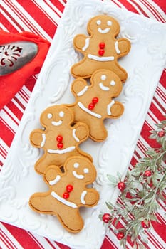 Gingerbread men served on an embossed tray on a candy cane striped tablecloth.