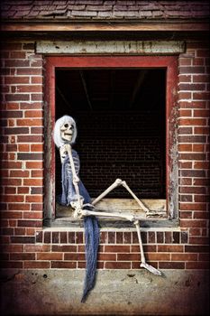 A female skeleton posing like a pinup girl in the window of an old abandoned home.