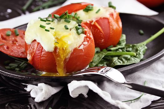 Eggs with mozzarella cheese baked in fresh tomatoes and garnished with chives. Extreme shallow depth of field.