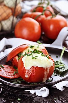 Eggs with mozzarella cheese baked in fresh tomatoes and garnished with chives. Extreme shallow depth of field.