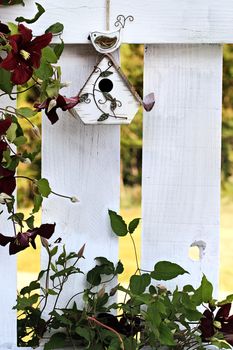 Cute little birdhouse on an old white wooden fence with extreme shallow depth of field.