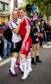 BERLIN, GERMANY - JUNE 21, 2014:Christopher Street Day.Elaborately dressed people participate in the parade celebrates gays, lesbians, bisexuals and transgenders.Prominent in the image are a gay couple in heels, dressed as football players.