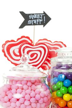 A closeup of part of a candy buffet with a variety of candies in apothecary jars.  Shot on white background.