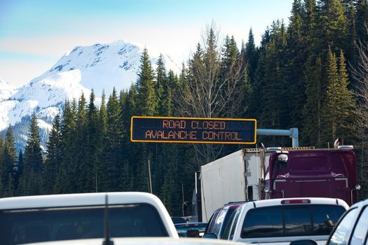 Travel through Roger's Pass in spring.  Traffic is stopped while avalanches are triggered with explosives and then cleaned from the road to ensure safe travel. Roger's Pass, British Columbia, Canada.