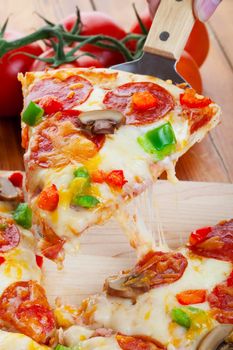 A slice of hot pizza deluxe with pepperoni, mushrooms, peppers, and lots of gooey mozzarella cheese, ready to be served.