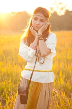 Hippie woman posing in golden field on sunset