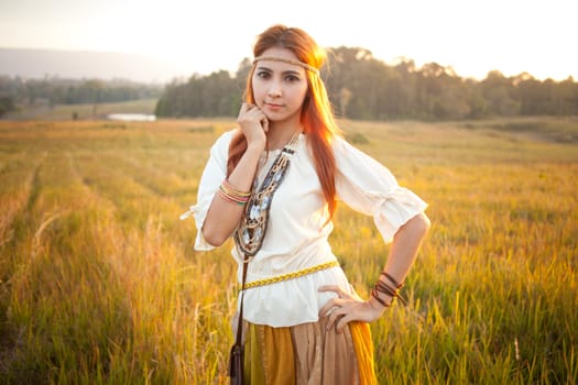 Hippie woman posing in golden field on sunset