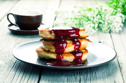 Delicious pancakes with raspberries sauce on the wooden kitchen table