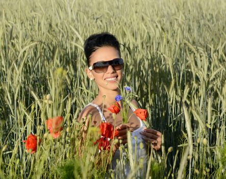 lauging young  woman with bouquet in cornfield