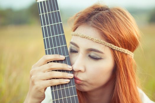 Close up of Pretty country hippie girl with guitar on grass