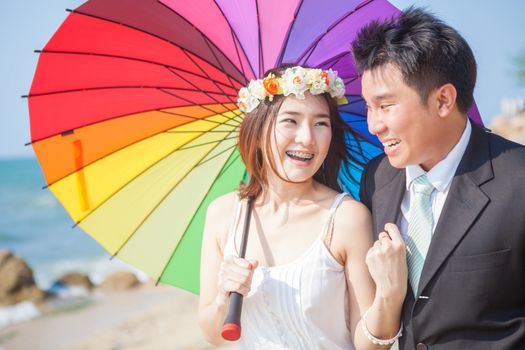 Beautiful asian couple on the beach in wedding dress