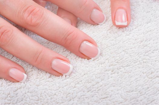 Fingers with french manicure on white towel