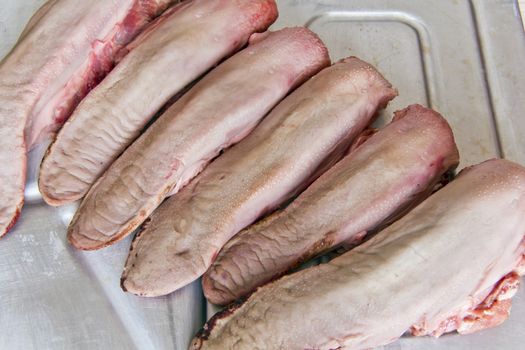 Photo of raw pork tongue on grey background