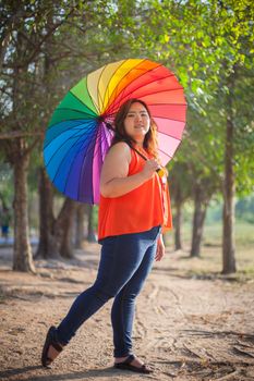 Happy fatty asian woman with umbrella outdoor in a park