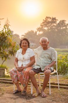 Happy Asian Senior couple sitting outdoors on sunset