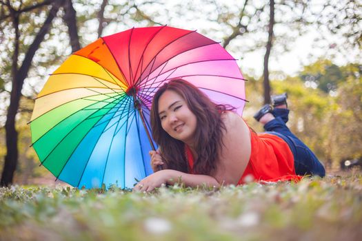 Happy fatty asian woman with umbrella outdoor in a park