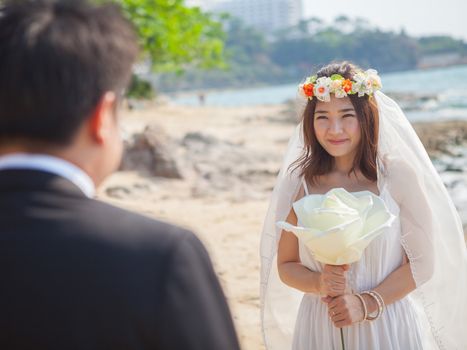 Beautiful asian couple on the beach in wedding dress