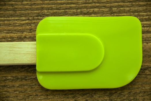 A bright green silicone spatula on a wooden board