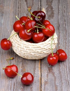 Red Ripe Sweet Cherries in Wicker Bowl isolated on Rustic Wooden background