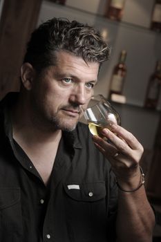 Winegrower in wine-cellar holding glass of wine