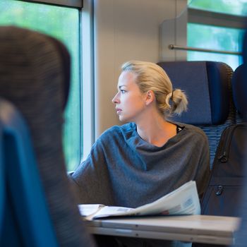 Thoughtful young lady reading while traveling by train.