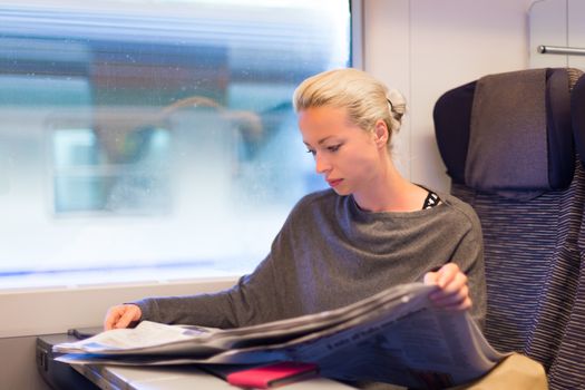 Thoughtful young lady reading while traveling by train.