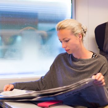 Thoughtful young lady reading while traveling by train.