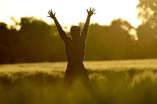 Little Boy Freedom jumping in wheat field at sunset