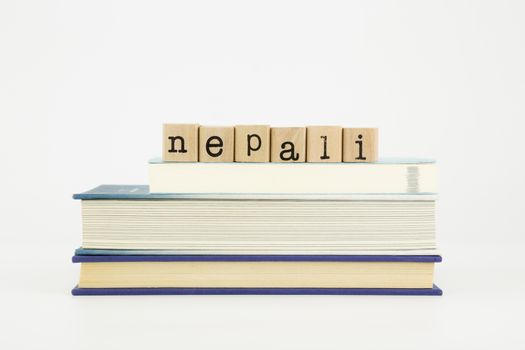 nepali word on wood stamps stack on books, language and study concept