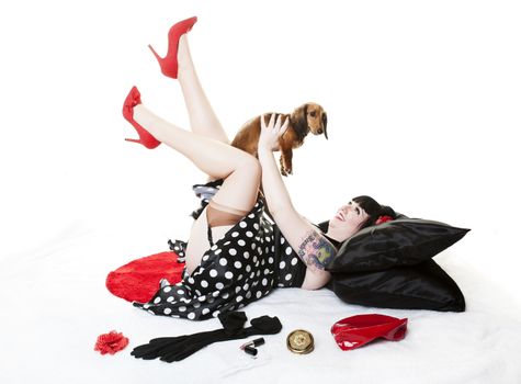 Vintage inspired, retro pinup girl holding her Dachshund puppy above her.
