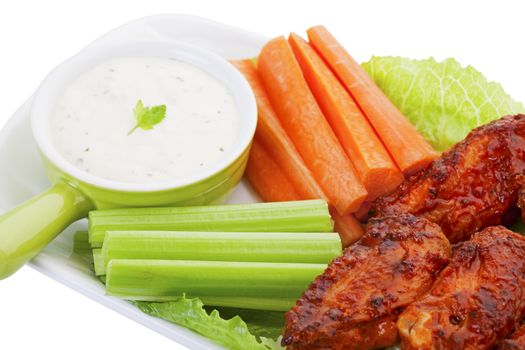 Succulent hot wings served on a bed of lettuce, with fresh carrot and celery sticks.  A cool ranch dip for the vegies, garnished with a sprig of Italian parsley, compliments the hot flavor of the wings.  Shot on white background.